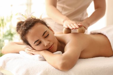 Genç Afro-Amerikalı kadın spa salonunda terapistin taşaklarıyla masaj yaptırıyor.