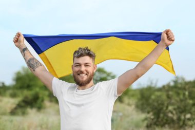 Açık havada Ukrayna bayrağı taşıyan mutlu genç adam.
