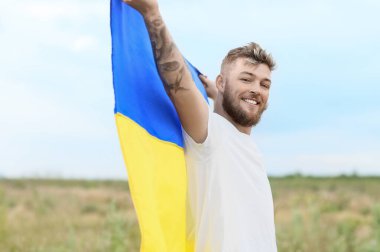 Açık havada Ukrayna bayrağı taşıyan mutlu genç adam.