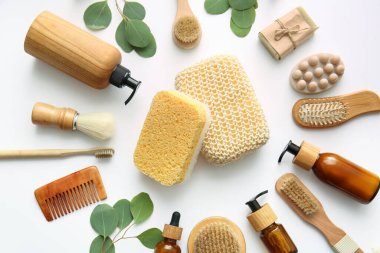 Süngerli banyo malzemeleri ve beyaz arka planda bitki dalları.