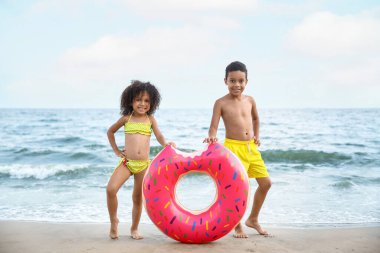 Deniz kıyısında şişme yüzüklü Afro-Amerikalı çocuklar.