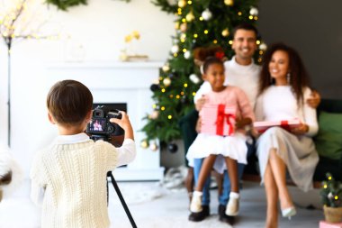 Küçük çocuk Noel arifesinde ailesinin fotoğrafını çekiyor.