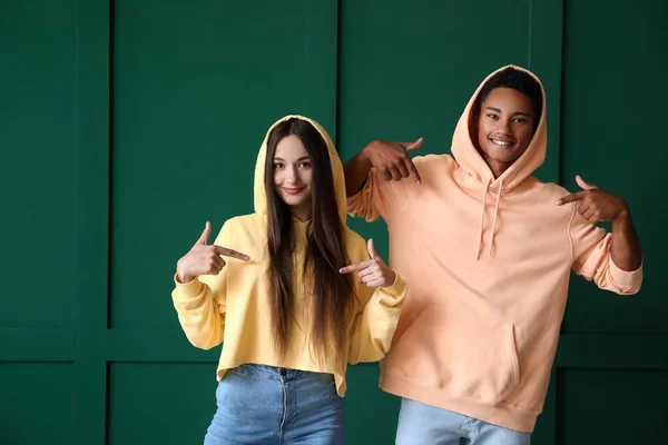 Elegante Jovem Casal Apontando Para Capuzes Fundo Verde — Fotografia de Stock