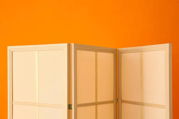 橙色墙壁附近的现代折叠屏幕 — 图库照片