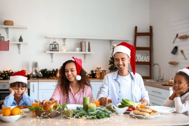 Mutlu bir aile mutfakta Noel yemeği yiyor.