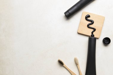 Aktif karbon diş macunu ve arka planda bambu diş fırçası olan tüpler, yakın plan.