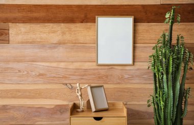 Yeşil kaktüs, ahşap duvarın yanında çerçeveli ve mankenli bir masa.