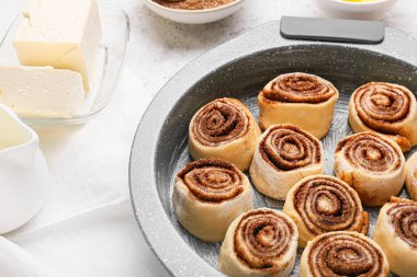 Beyaz arkaplanda pişmemiş tarçınlı rulo pişirme tabağı, yakın plan