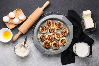 Pişmemiş tarçınlı rulo ve siyah beyaz arka planda malzemelerle pişirme