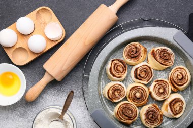 Pişmemiş tarçınlı rulo ve siyah beyaz arka planda malzemelerle pişirme