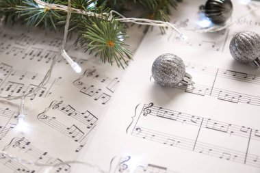 Parlayan ışıklarla Noel baloları ve nota kağıtlarında köknar dalları