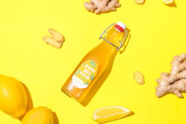 Sarı arka planda limon ve zencefilli bir şişe lezzetli kombu çayı.