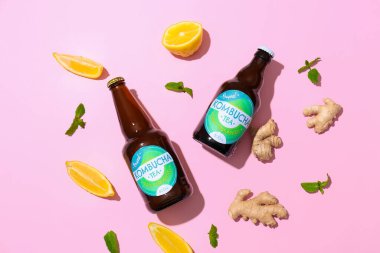 Pembe arka planda limon ve zencefilli taze kombu çayı şişeleri