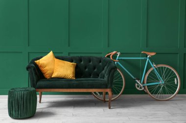 Yeşil duvarın yanında puf ve bisikletli kanepe