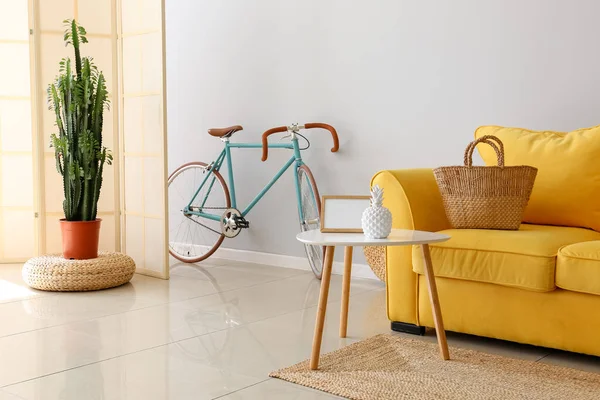 Interior of light living room with yellow sofa and bicycle