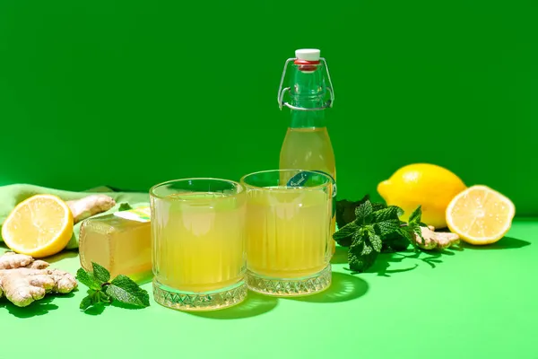 緑の背景にレモンと生姜を入れたフレッシュコンブ茶のグラス — ストック写真