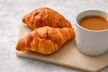 Lezzetli kruvasan ve hafif arka planda bir fincan kahve.