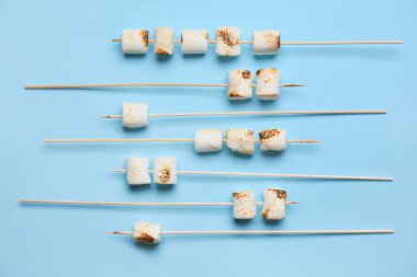 Lezzetli ızgara marşmelovlu şişler mavi arka planda