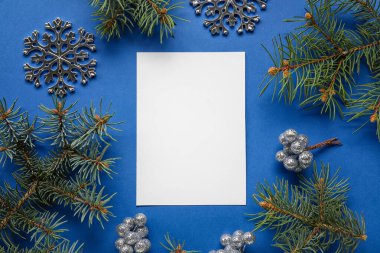 Köknar dalları ve mavi arka planda Noel dekoru olan boş kart