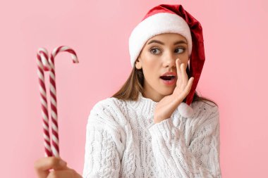 Noel Baba şapkalı ve renkli baston şekerli genç bir kadın.