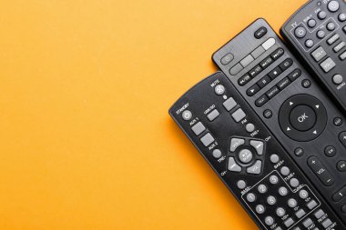 Turuncu arkaplanda farklı TV uzaktan kumandaları