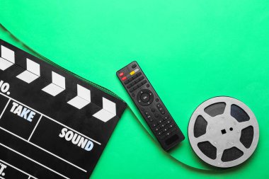 Yeşil arka planda film makarası ve el çırpma tahtası olan modern TV uzaktan kumandası