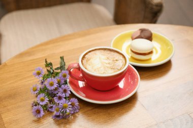 Kafedeki masada bir fincan lezzetli kahve ve asters çiçekleri.