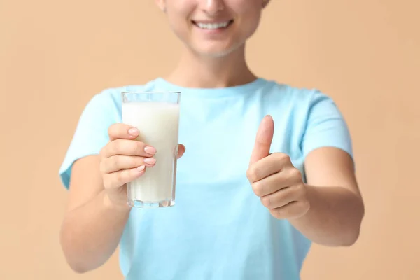 年轻女子与一杯有机牛奶显示大拇指特写手势的色彩背景 — 图库照片