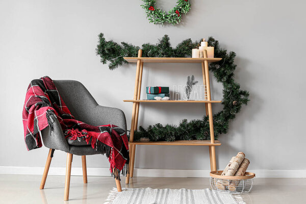 Shelving unit with beautiful Christmas decor and armchair in room