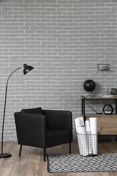 灰色のレンガの壁の近くの黒いアームチェアとランプ — ストック写真