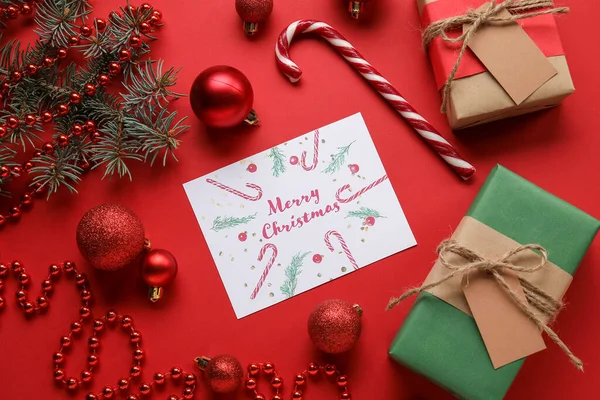 テキストとグリーティングカードメリークリスマス モミの木の枝 赤の背景に装飾やギフトボックス — ストック写真