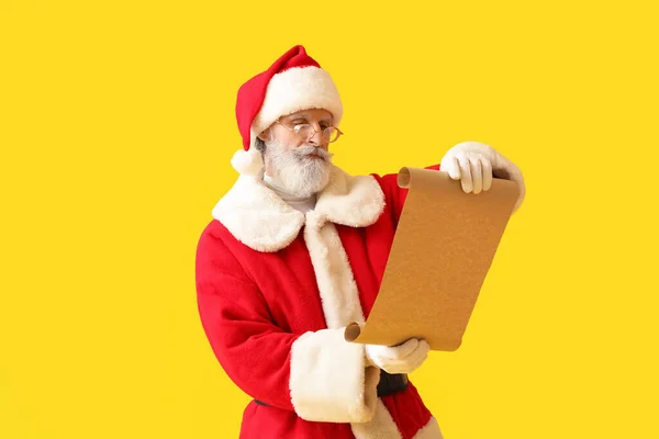 Weihnachtsmann Liest Wunschliste Auf Gelbem Hintergrund — Stockfoto