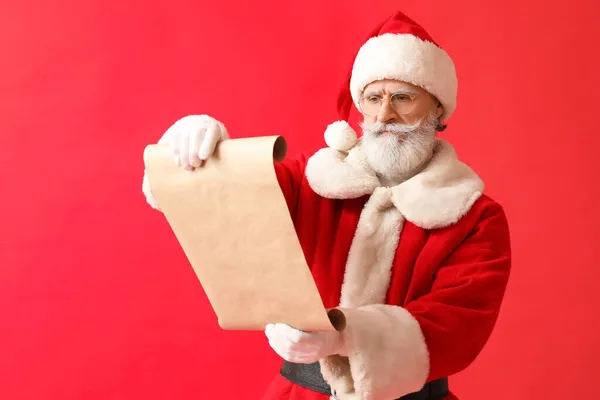 Weihnachtsmann Liest Wunschliste Auf Rotem Hintergrund — Stockfoto