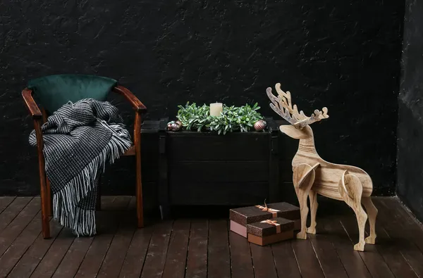 木製のトナカイ アームチェア ギフトボックス クリスマスリースと暗い壁の近くのキャンドル付きのテーブル — ストック写真