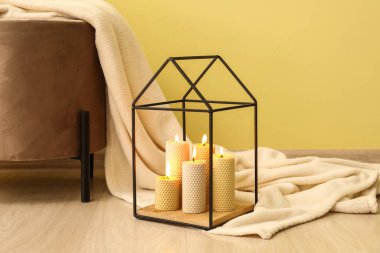 Renkli duvarın yanında yanan mumlar ve ekoseli puf.