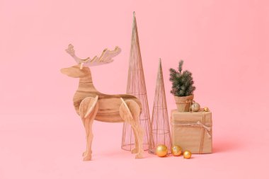 Küçük Noel ağacı olan ahşap ren geyiği, pembe arka planda mevcut ve dekor
