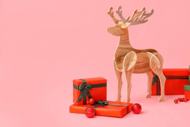 Pembe arka planda Noel hediyeleri olan tahta ren geyiği
