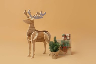 Tahta rengeyiği, küçük Noel ağacı ve bej arka planda hediyeler.