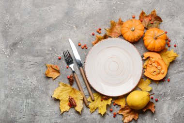 Gri arkaplanda masa düzenine, balkabaklarına ve sonbahar yapraklarına sahip kompozisyon