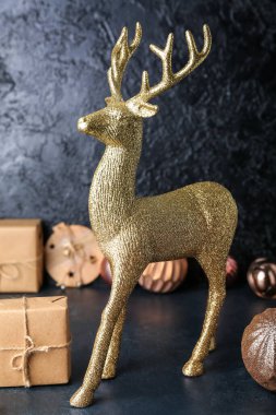 Koyu arkaplanda Noel hediyesi olan altın ren geyiği