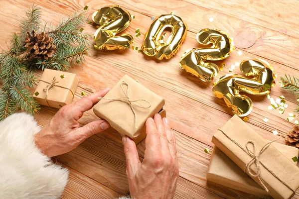 木製の背景に図2022の形でクリスマスプレゼントや風船とサンタクロース — ストック写真