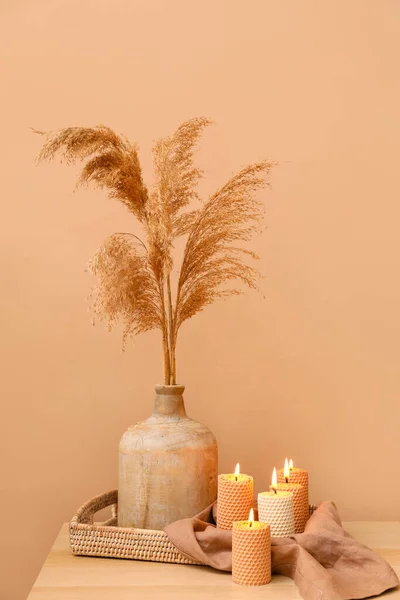 色壁の近くの木製のテーブルの上に葦の花とキャンドルや花瓶を燃焼 — ストック写真