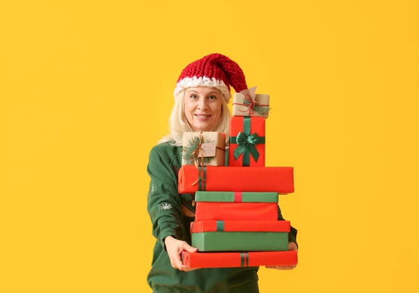 色の背景にクリスマスのギフトボックスを持つ熟女 — ストック写真