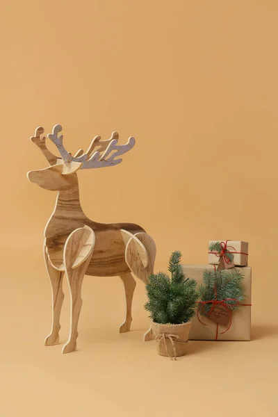 木のトナカイと小さなクリスマスツリーとベージュの背景にプレゼント — ストック写真