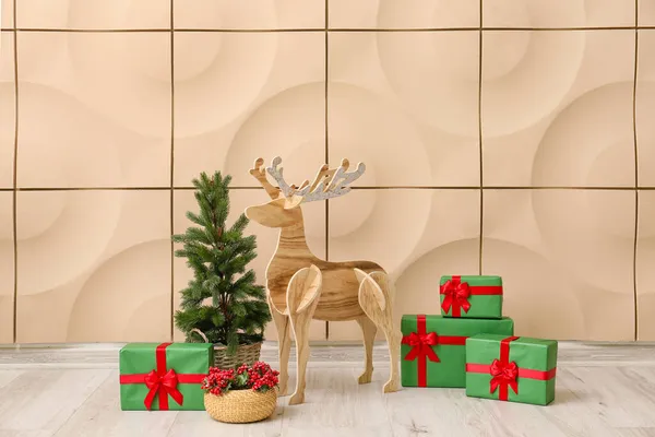 木のトナカイとクリスマスツリー ローワンとベージュの壁の近くにプレゼント — ストック写真