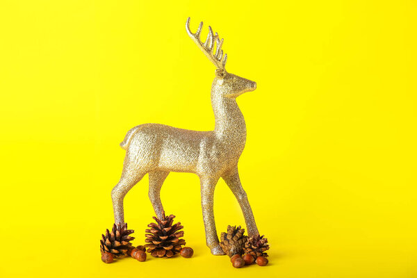 Golden reindeer with fir cones and chestnuts on yellow background