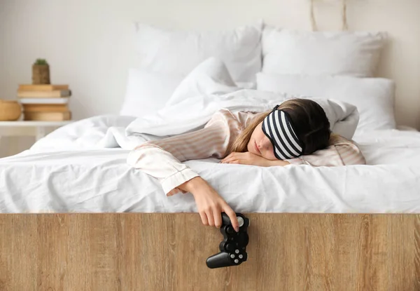 睡意朦胧的年轻女子 带着电子游戏控制器躺在床上的早晨 — 图库照片