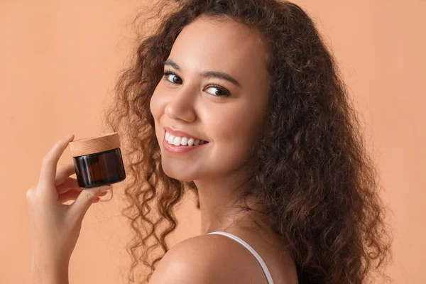 Renkli kavanozda kremi olan güzel Afro-Amerikalı kadın.