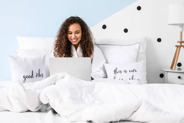 一个拿着笔记本电脑坐在床上的年轻女人的早晨 — 图库照片