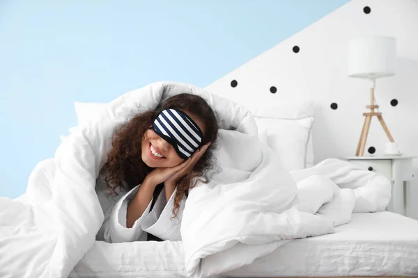 带着睡眠面具的年轻女子躺在床上 — 图库照片